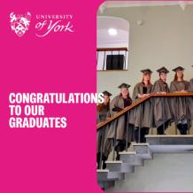 Photo of some of our graduation in their graduatution gowns standing on the Heslington Hall staircase